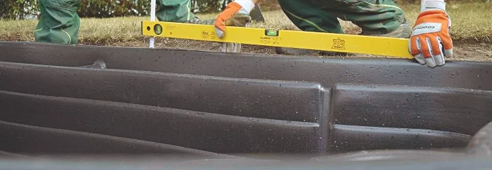 Person beim Bau eines Teichs mit Wasserwaage